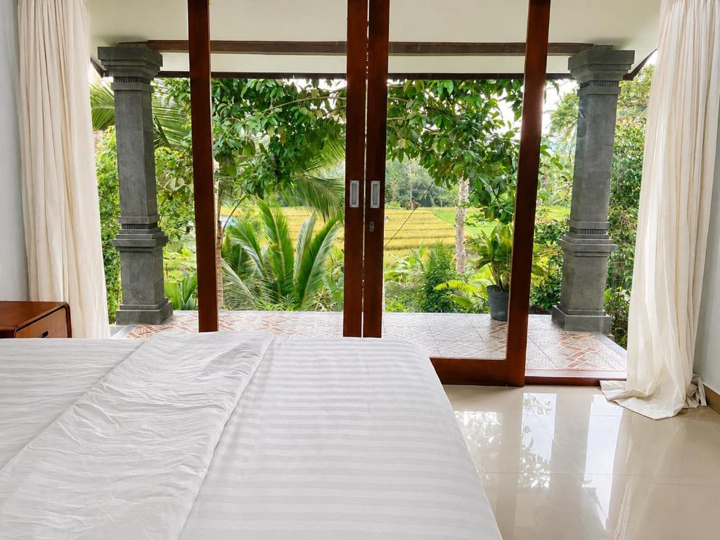 a bedroom with a large bed and a large window at Bendul Retreat in Tabanan