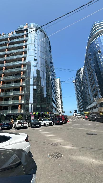 a city street with cars parked in front of tall buildings at у моря in Batumi