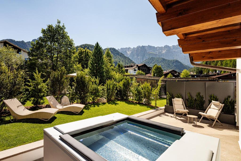 a backyard with a swimming pool and a patio with chairs at Boutique Hotel Nives - Luxury & Design in the Dolomites in Selva di Val Gardena