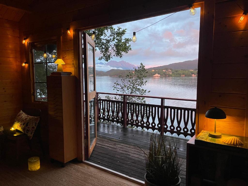 a door to a balcony with a view of a lake at Fjord View Off-Grid Cabin in Ålesund