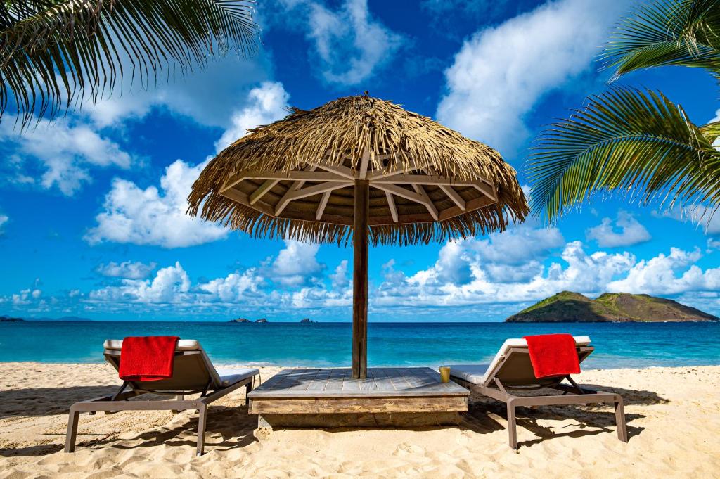 two chairs under an umbrella on the beach at Hôtel Baie des Anges in Gustavia