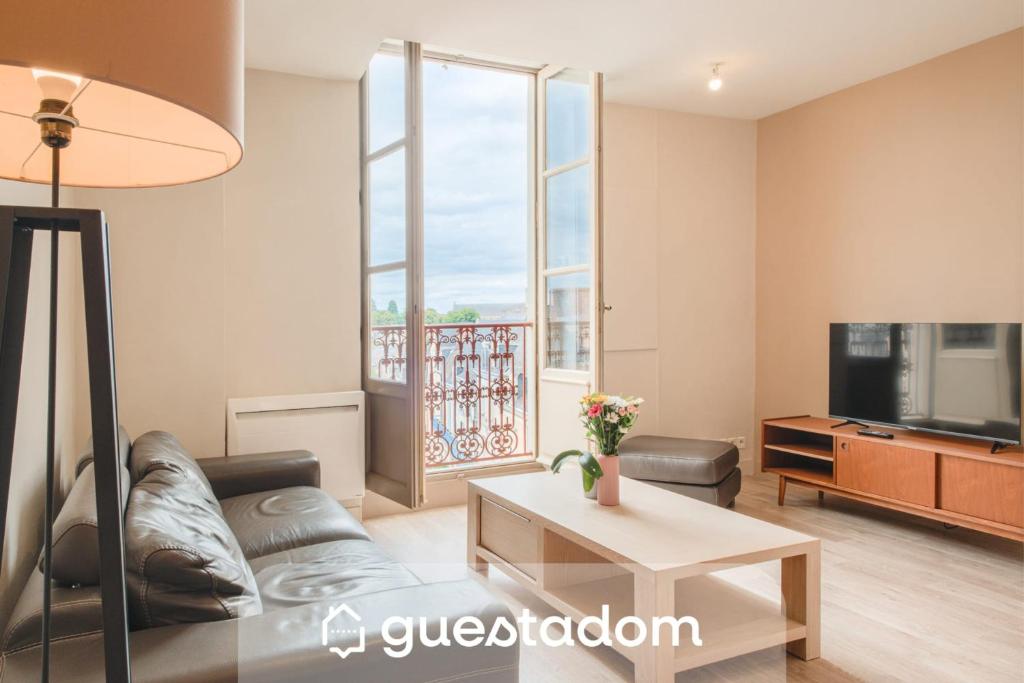 a living room with a couch and a tv at Le Doumer - Centre-ville - Petfriendly in Château-Gontier