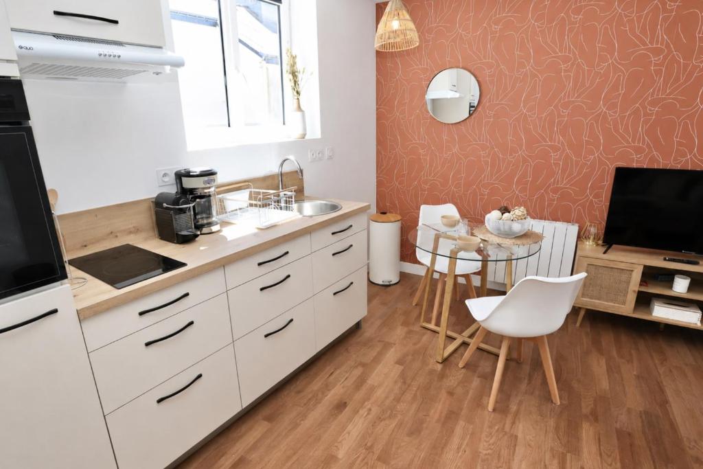 a kitchen with white cabinets and a table and a tv at Le Corail - centre-ville - TV in Pontivy