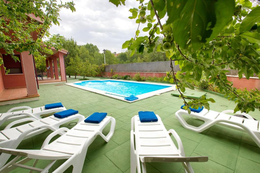 a group of white chairs and a swimming pool at Cuencaloft Villa Los Perales in Villalba de la Sierra