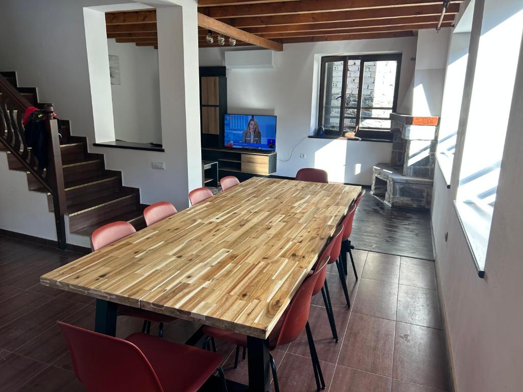 a wooden table in a room with red chairs at Валериевата Къща 2 in Shiroka Laka