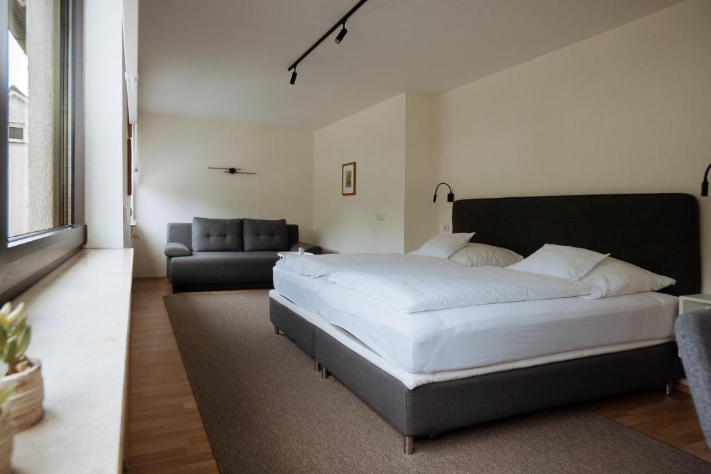 a bedroom with a large white bed and a couch at Hotel Am Waldschwimmbad in Bürstadt
