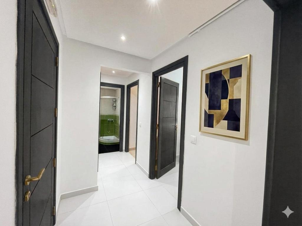 a hallway with black doors and white walls and a bathroom at Splus1 in Nabeul