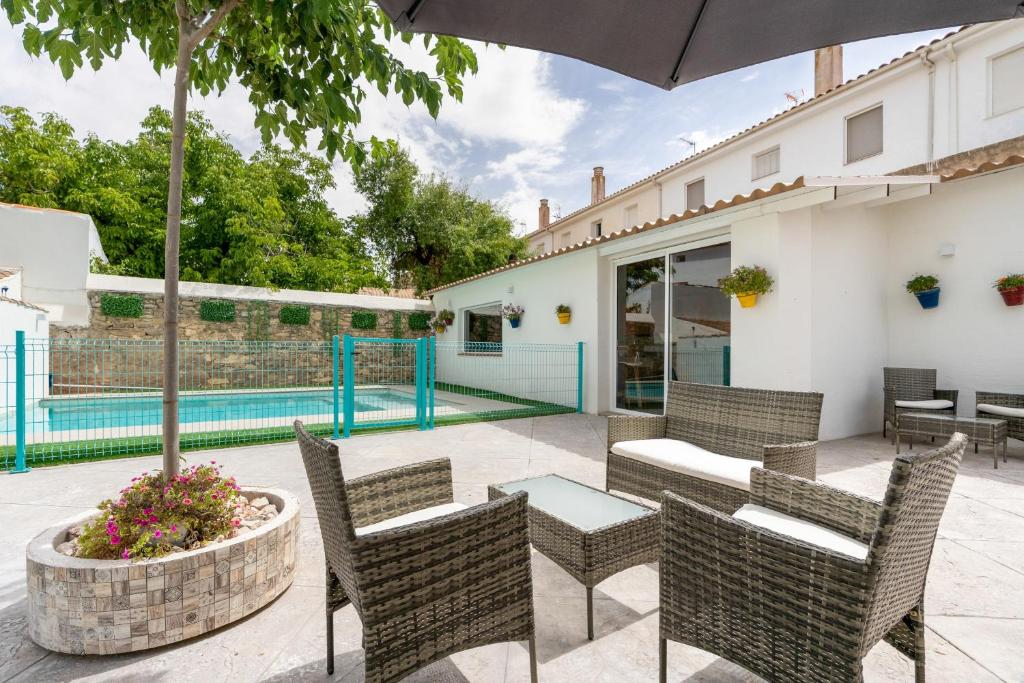 a patio with chairs and an umbrella and a pool at Raízes 22 - Apartamento 5 in Puebla de Don Fadrique