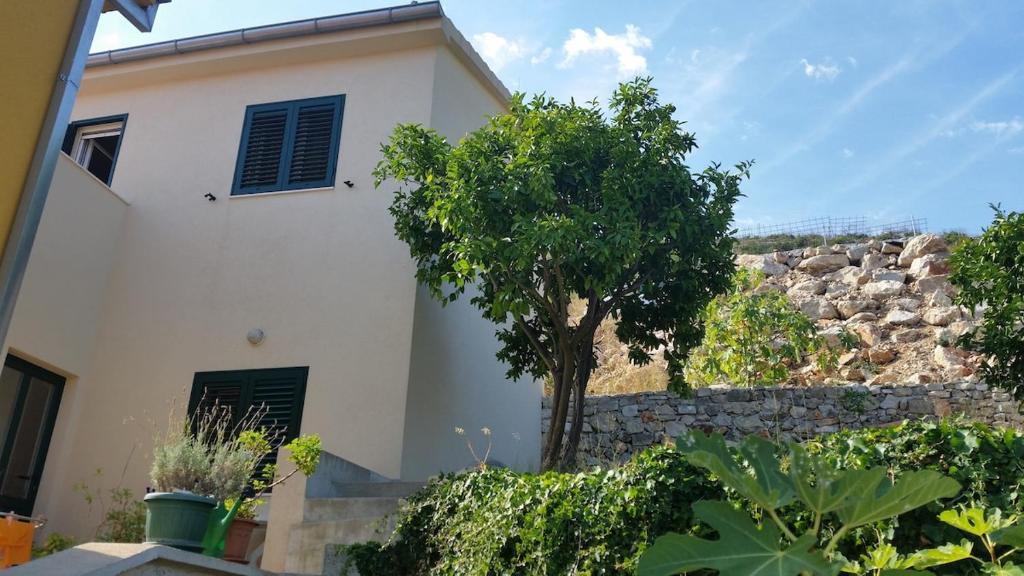 a white house with a tree and a stone wall at Hilly house - Vis in Vis