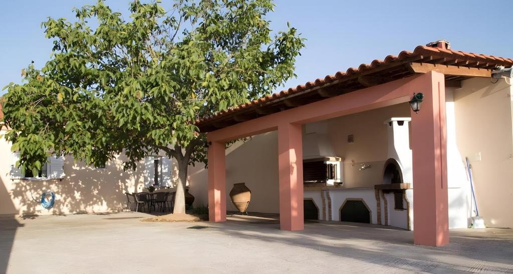 a building with red columns and a tree at Evoia Village House in Neokhórion