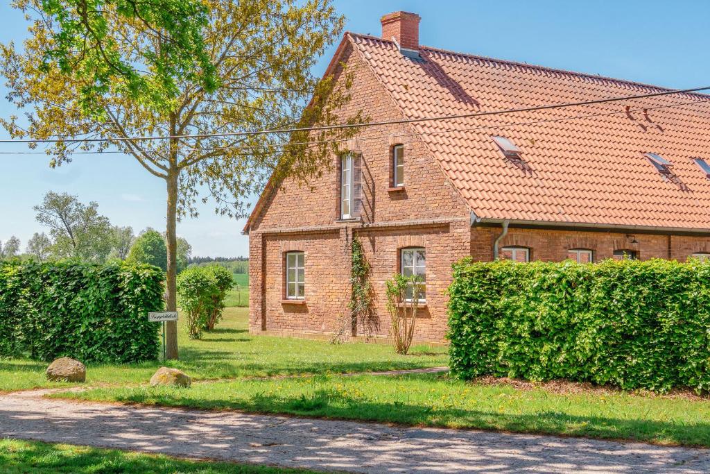 ein altes Backsteinhaus mit einer Hecke davor in der Unterkunft Ferienwohnung Koppelblick III - Boldevitzer Rügenkaten in Parchtitz