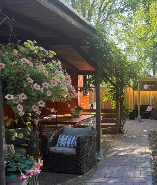 a patio with a wicker chair under a pergola at Casa Rosa - Sfeervolle cottage met jacuzzi in Erm