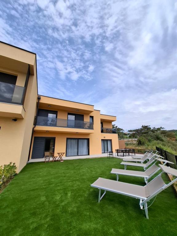 a building with a green lawn in front of it at Paradiso Beach House in Lopar