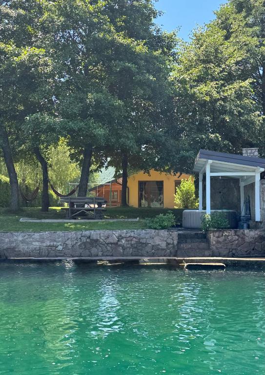 a house with a picnic table next to a body of water at Holiday home Emma in Ripač