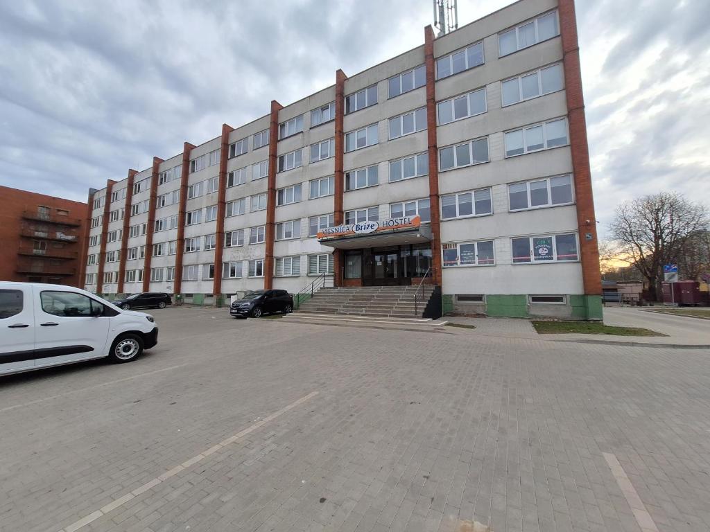 a white van parked in front of a large building at LionEstateHostel in Liepāja