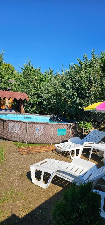 a group of white lounge chairs and a swimming pool at Cabana Relax in Râmnicu Vâlcea