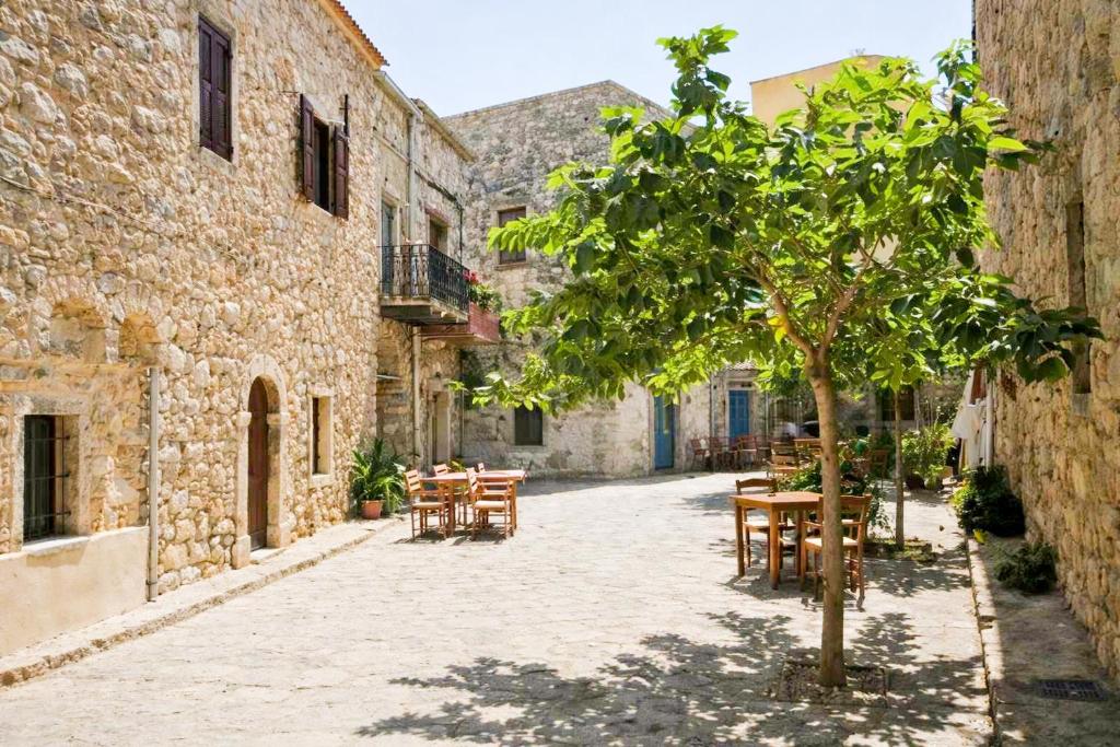 a courtyard with tables and a tree in an alley at Vlychos Olympi Lodges - Chios Cozy Getaways in Olýmpoi