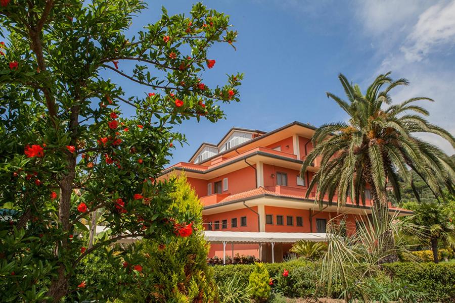 a large orange building with a palm tree in front of it at Hotel Le Rotonde in Massaciuccoli