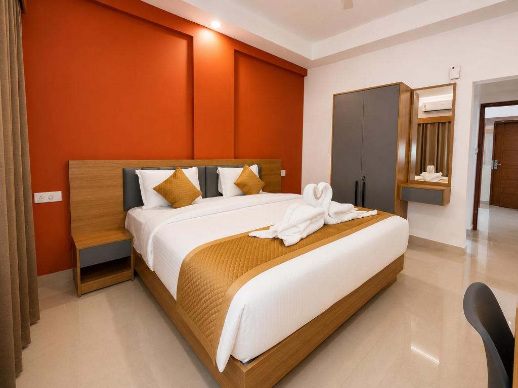 a bedroom with a large bed with orange walls at Nova Alhind Airport Hotel Cochin in Nedumbassery