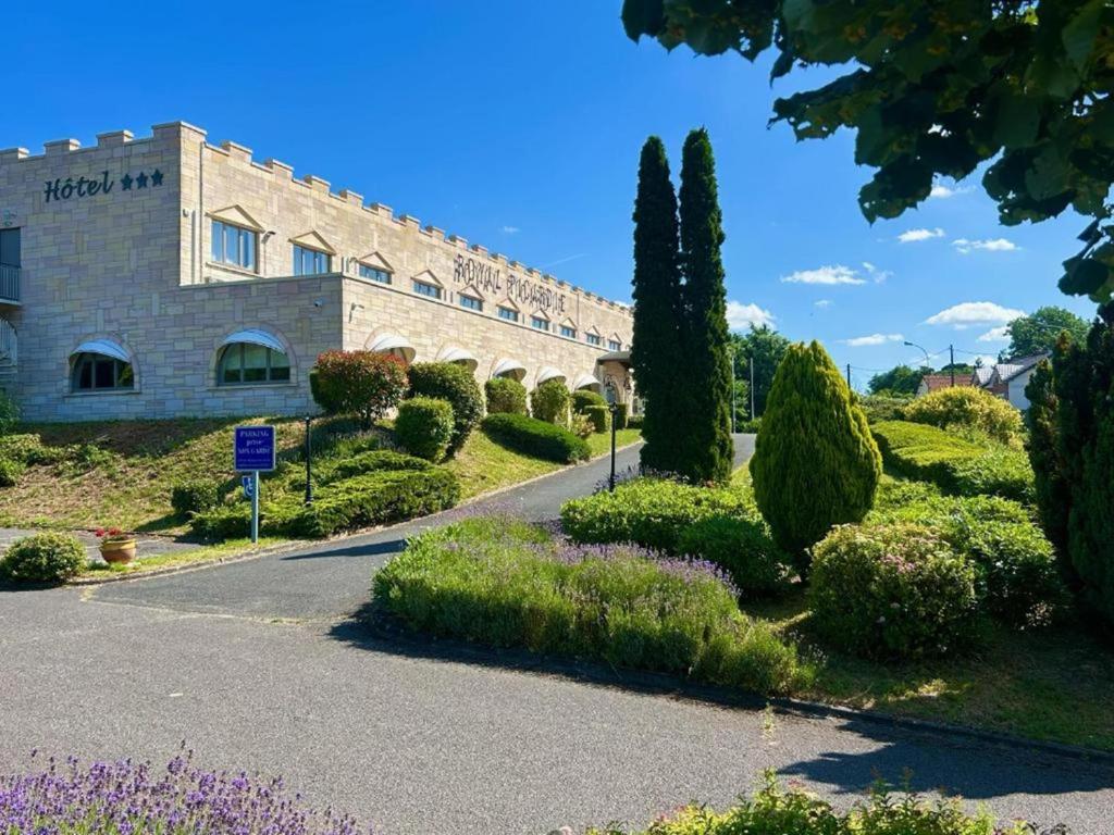 a building with trees and bushes in front of a road at Le Royal Picardie, BW Signature Collection in Albert