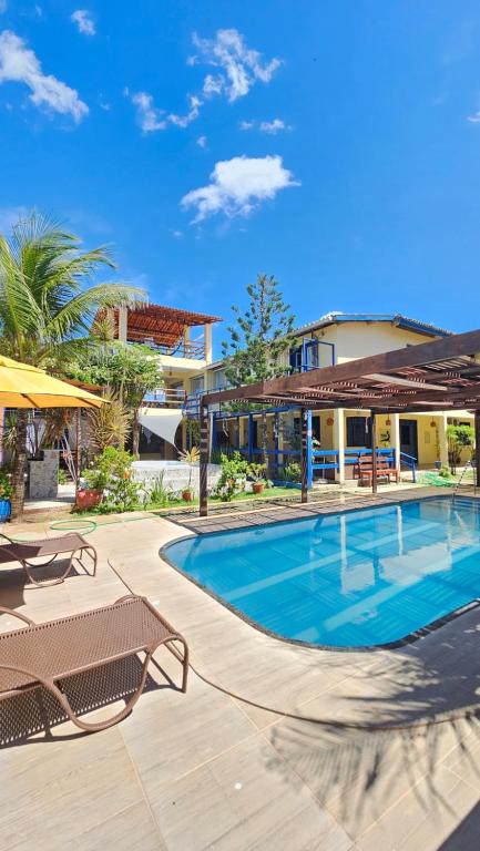 a swimming pool with chairs and a building at Shanti Om Refúgio Pousada e Yoga in Cascavel
