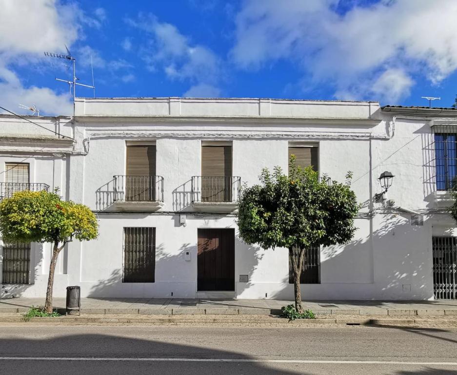 a white building with two trees in front of it at Casa Rural El Pergareo in Cazalla de la Sierra