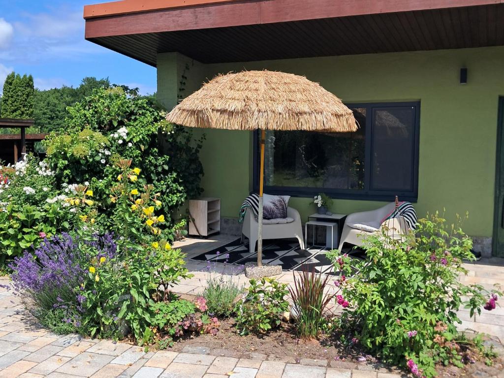 a patio with two chairs and a straw umbrella at Ferienbungalow Haus Rolf _ Objekt in Papendorf
