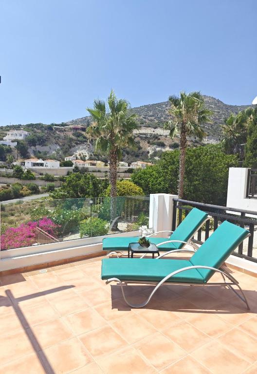 a pair of blue lounge chairs on a balcony with palm trees at Sun Set at Coral Bay in Peyia