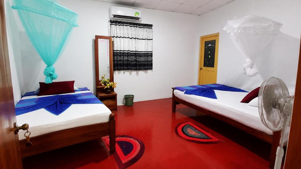 two beds in a room with a red floor at Green Grass Homestay in Sigiriya