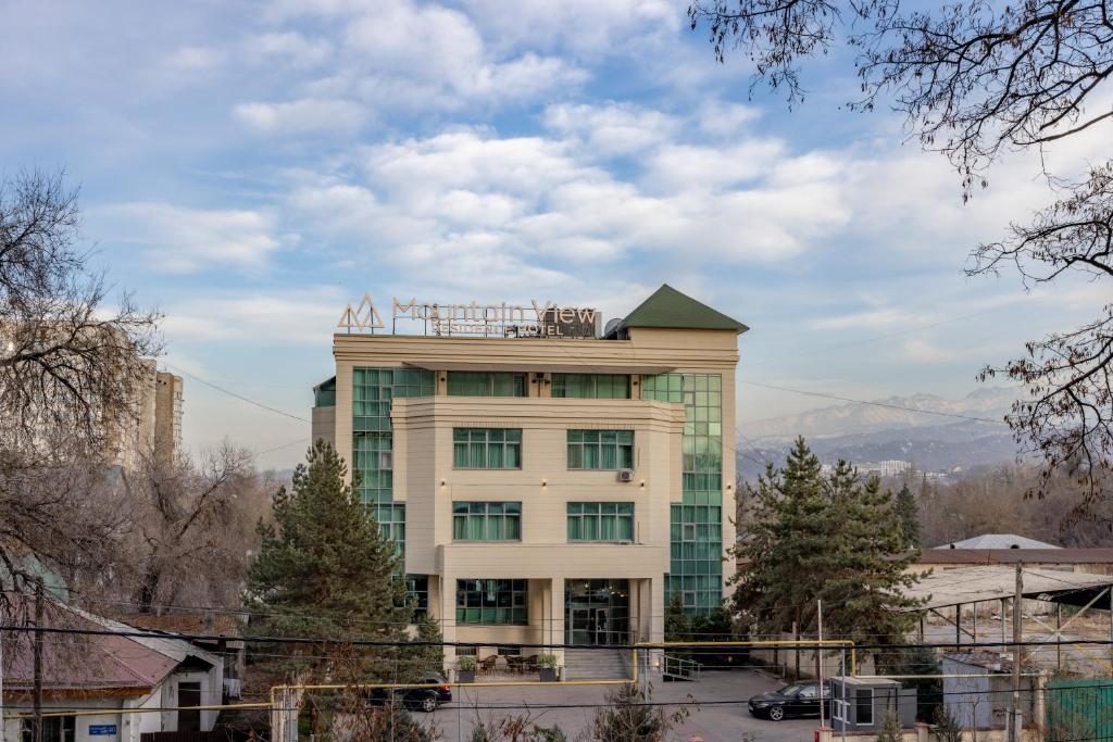 a building with a sign on the top of it at Mountain View Residence Hotel in Almaty