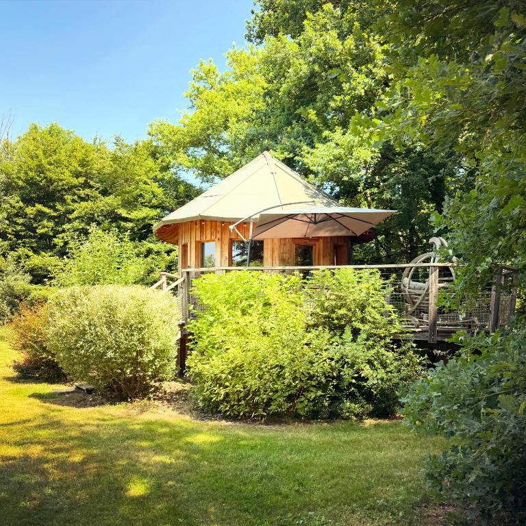 a gazebo with an umbrella in a garden at Le P’tiot Utau in Chapelle-Voland