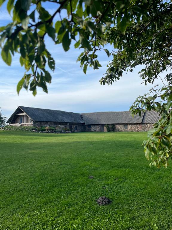 an old barn with a green field in front of it at Grandma's Attic in Saraiķi