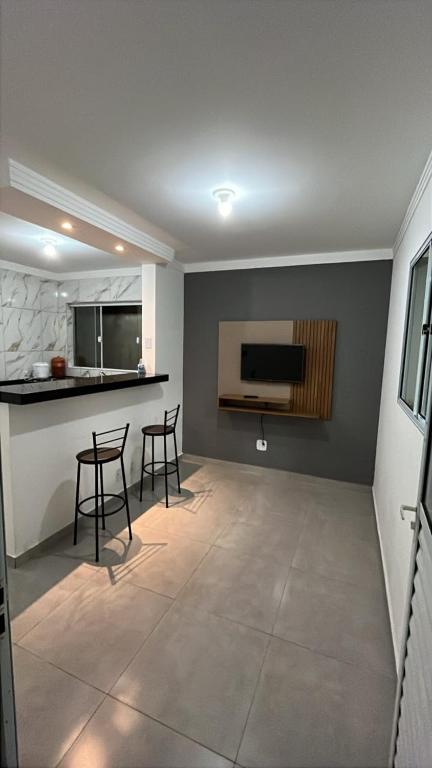a living room with two stools and a kitchen at Lar Tranquilo Com Garagem in Pirassununga