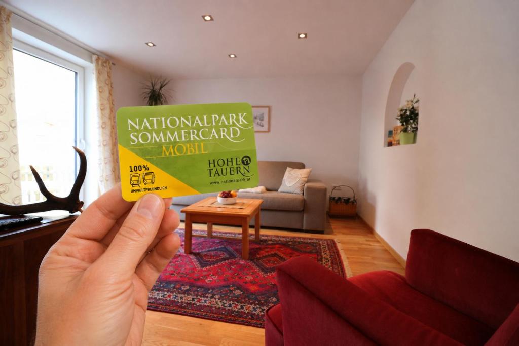 a person holding up a sign in a living room at Ferienwohnung Bräu in Rauris