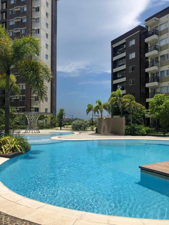 a swimming pool with palm trees and buildings at Cozy 2 Bedroom Condo with Balcony for Rent in Iloilo City
