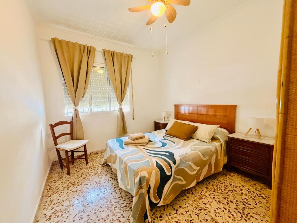 a bedroom with a bed and a chair and a window at Cala de Los Lobos in Puerto de Mazarrón