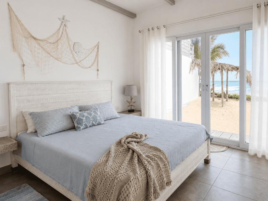 a bedroom with a bed with a view of the beach at Sandy Feet House in Puerto Villamil