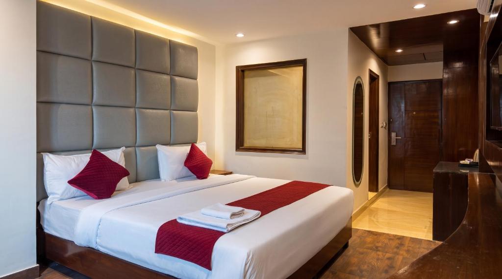 a bedroom with a large white bed with red pillows at The Chapter Hotel, Vasant Kunj in New Delhi