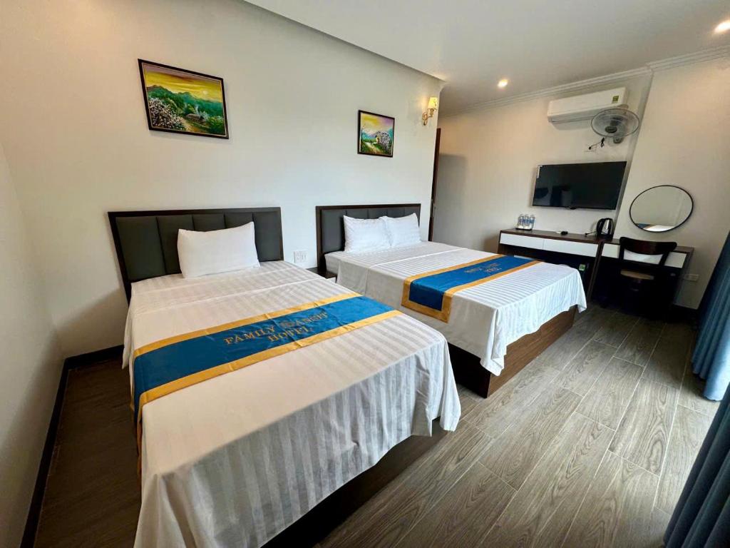 a hotel room with two beds and a television at Family Transit Hotel in Thach Loi