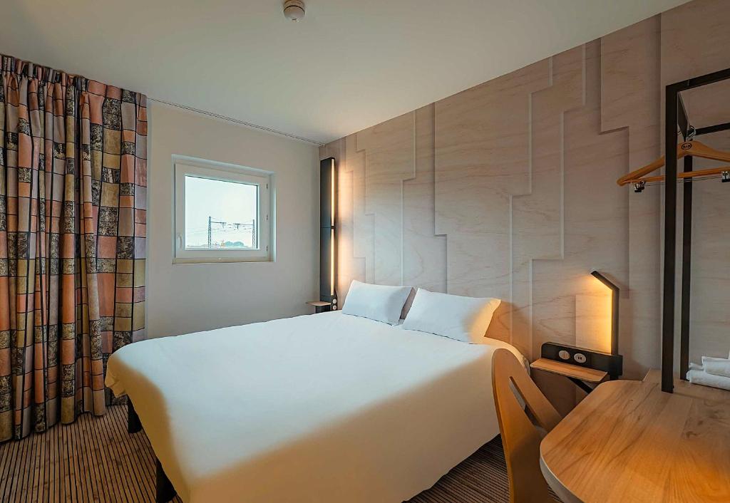 a bedroom with a large white bed and a wooden table at B&B HOTEL Mâcon Sud 3 étoiles in Varennes-lès-Mâcon