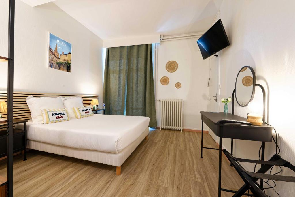 a hotel room with a bed and a desk at Hôtel en Ville in Autun