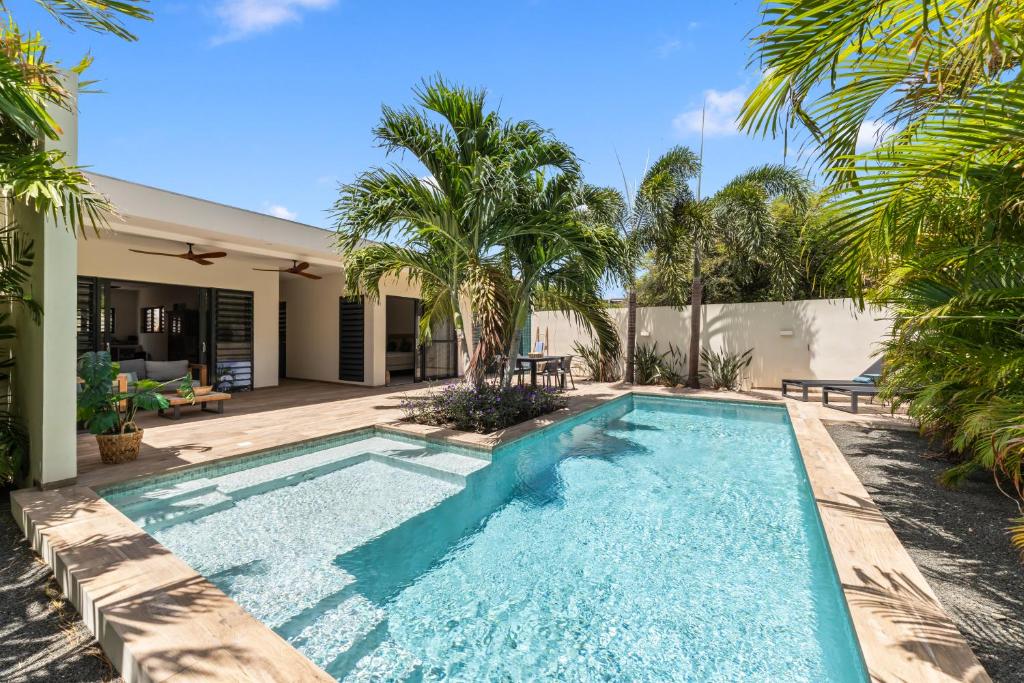 a swimming pool in the backyard of a house with palm trees at Luxe Tropische Villa met Privézwembad in Jan Thiel