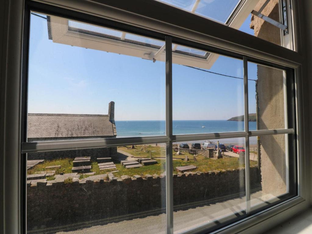 a window with a view of the ocean and a bench at 4 Bryn Llan in Pwllheli