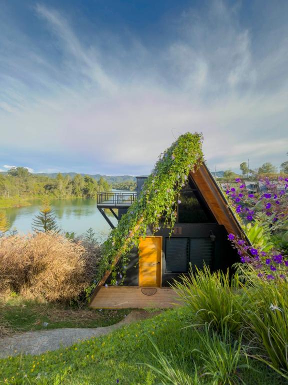 a house covered in ivy next to a body of water at GRETEL CHALETS SUIZO in Guatapé