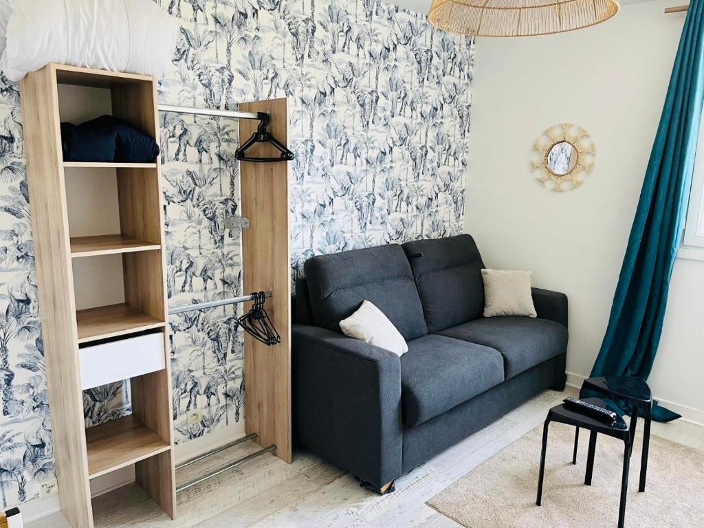 a living room with a blue couch in front of a wall at Studio centre ville in Concarneau