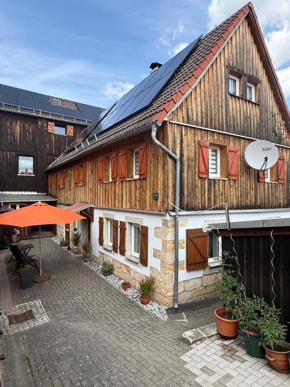 a large wooden house with a courtyard in front of it at Urlaub im Oberstübchen in Lichtenhain