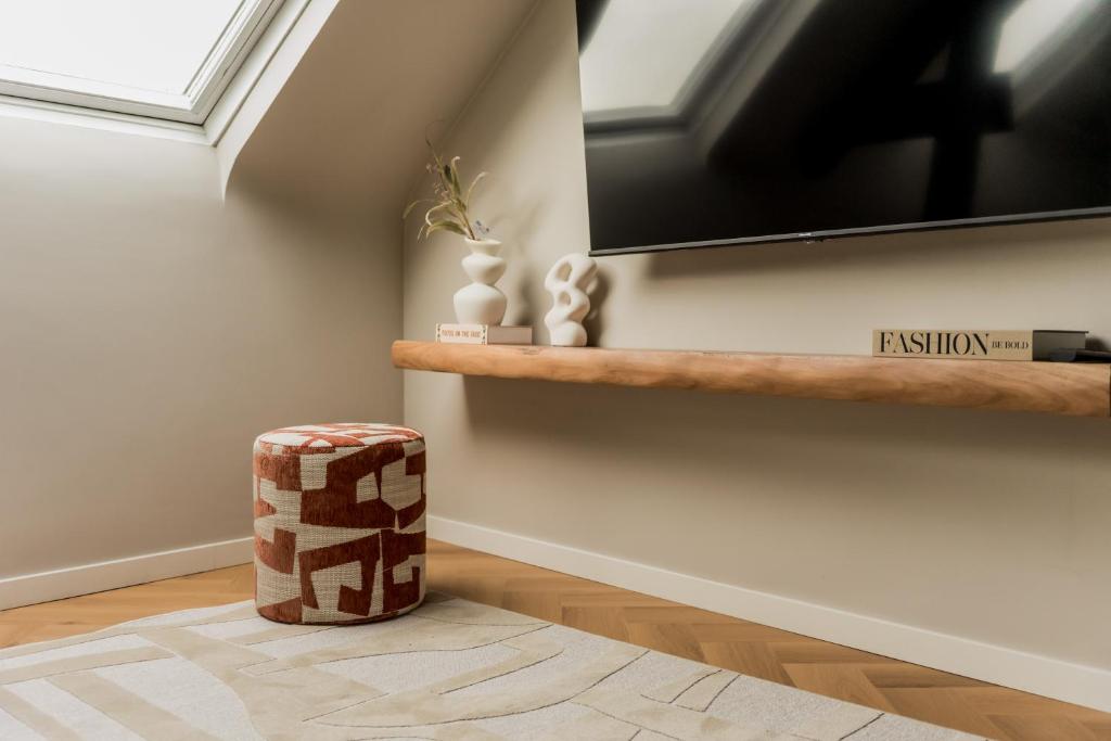 a living room with a television and a stool at Leeuwenhof Suites in Antwerp
