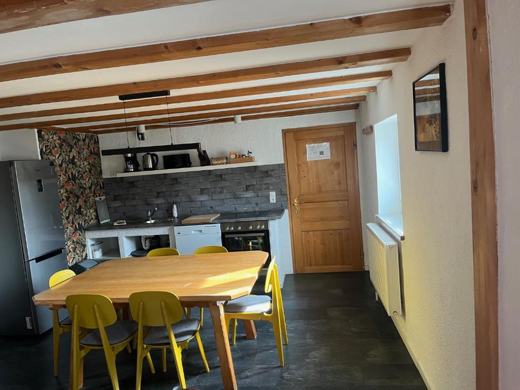 a kitchen with a wooden table and yellow chairs at Allgäuer Taucherhof in Aitrang