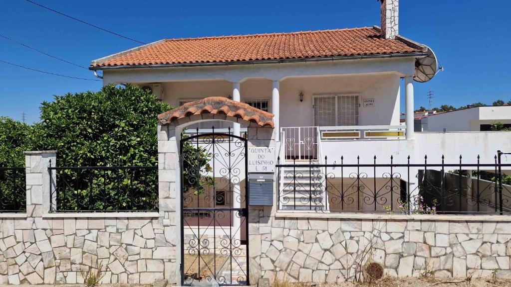 a white house with a gate and a fence at Vivenda Alves in Charneca