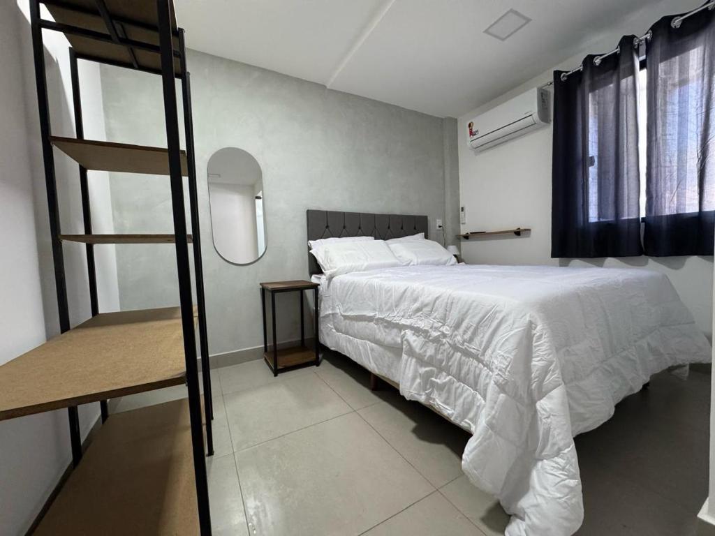 a bedroom with a large white bed and a mirror at M e M executivo in Ipatinga